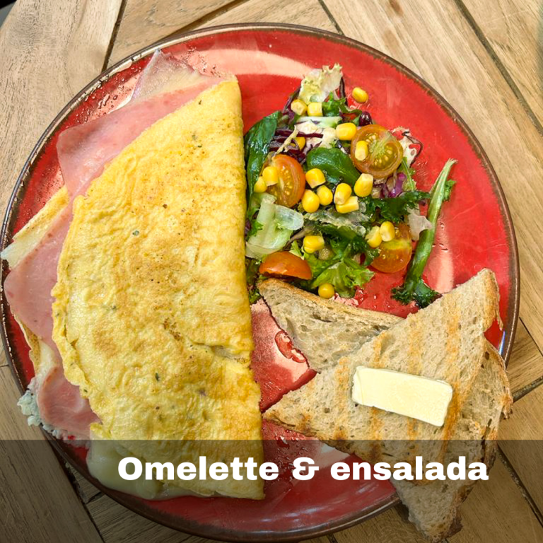 Tortilla francesa de huevos rellena de jamón york y queso gouda, acompañada de pan, mantequilla y ensalada